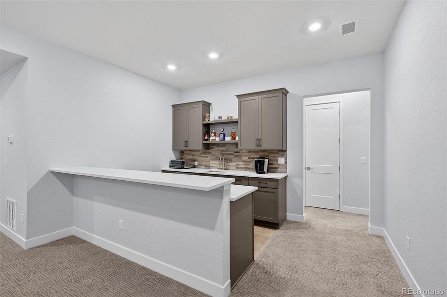 Basement Wet Bar (Front View) – Stylish wet bar featuring quartz countertops, tile backsplash, and upgraded cabinetry—perfect for entertaining guests.