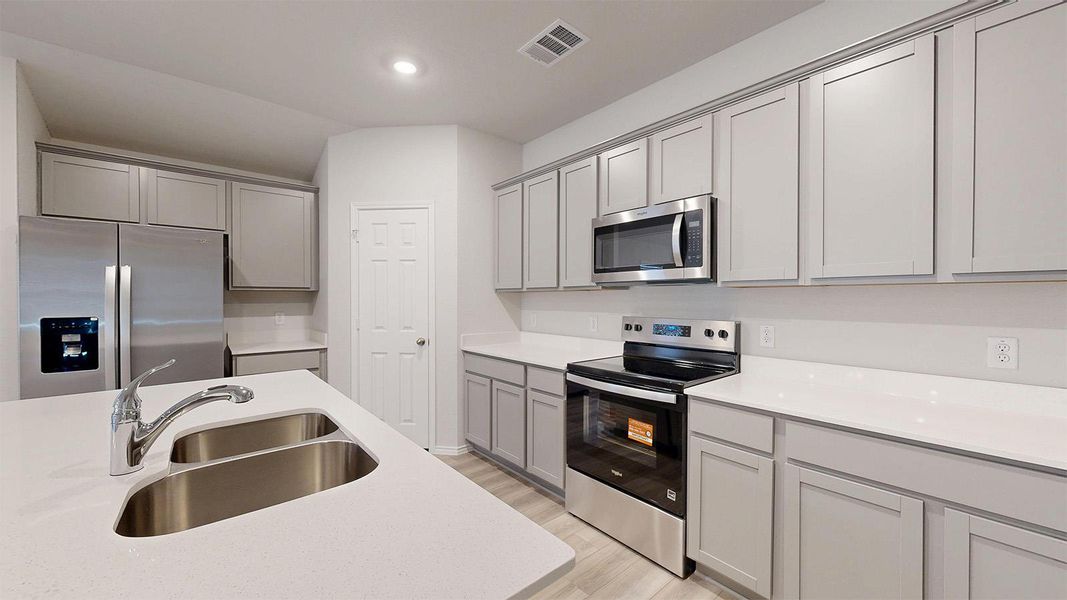 Culinary delights await in this modern kitchen, featuring pristine countertops and sleek stainless steel appliances.