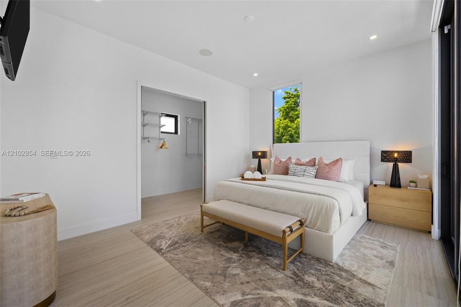 Wood-finish flooring, recessed lighting, vertical windows, and a walk-in storage area with integrated shelving