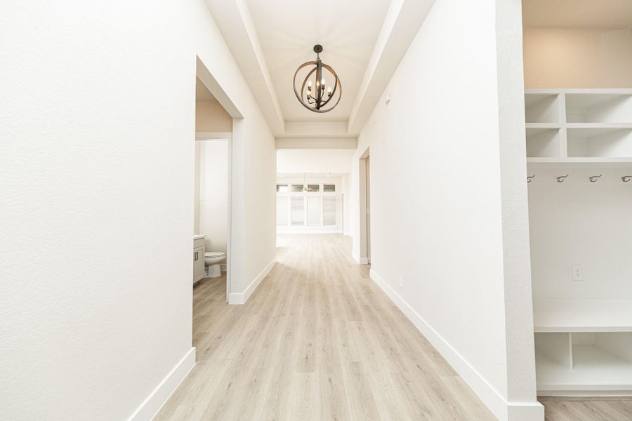 A well appointed mud room on your right is an essential feature for a busy household. The space boasts custom-built white cabinetry and shelving, providing generous storage for coats, bags, and shoes. A comfortable built-in bench offers a convenient spot to sit, while three sleek hooks keep outerwear tidy and accessible. A well appointed mud room on your right is an essential feature for a busy household. The space boasts custom-built white cabinetry and shelving, providing generous storage for coats, bags, and shoes. A comfortable built-in bench offers a convenient spot to sit, while three sleek hooks keep outerwear tidy and accessible.