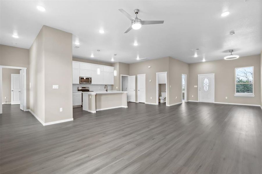 Unfurnished living room featuring ceiling fan, sink, and dark hardwood / wood-style flooring