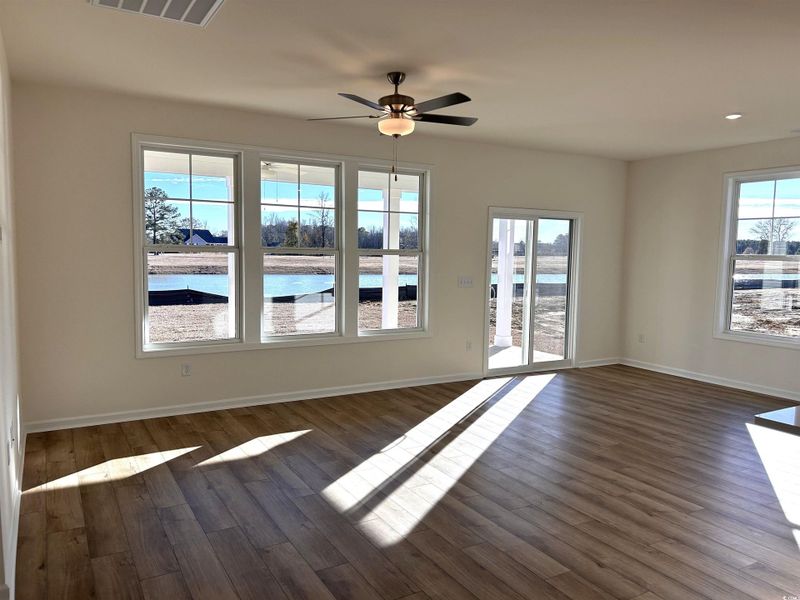 Unfurnished living room with dark wood finished floors, a ceiling fan, a water view, and recessed lighting