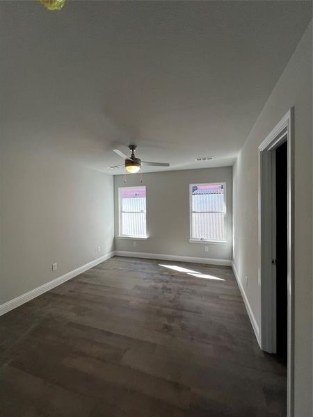 Unfurnished room featuring ceiling fan, a healthy amount of sunlight, and dark hardwood / wood-style floors