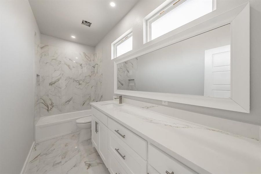 Full bathroom featuring vanity, toilet, and tiled shower / bath