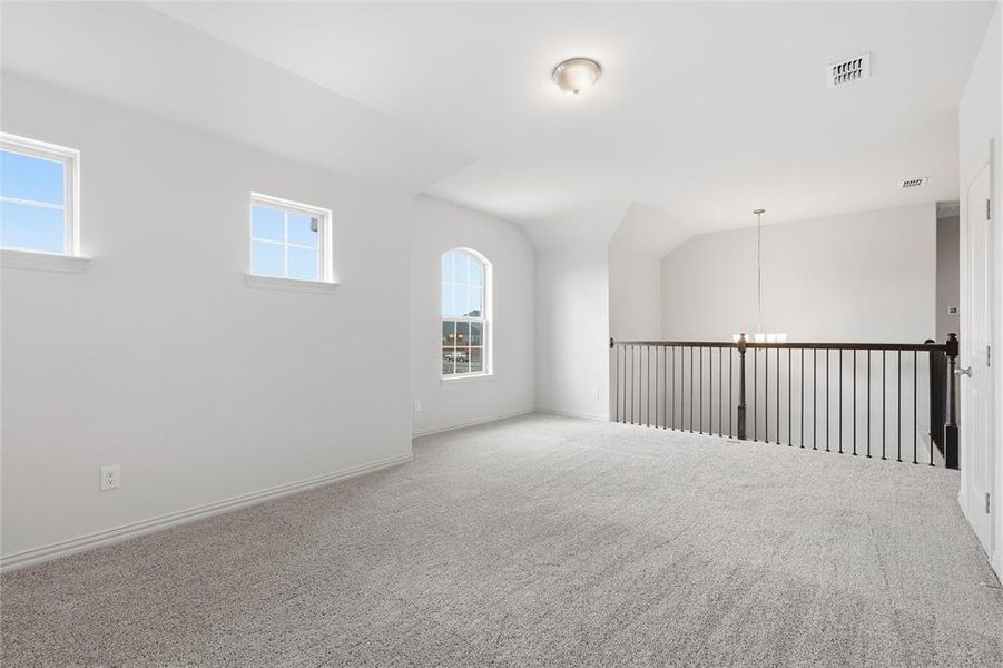 Empty room featuring a chandelier, carpet flooring, and vaulted ceiling Empty room featuring a chandelier, carpet flooring, and vaulted ceiling