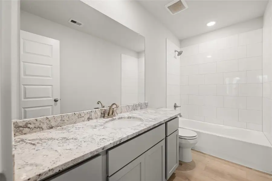 A sleek full bathroom showcasing a dual-sink vanity with granite countertops, ample storage, and a clean, modern design with a combination tub and shower. A sleek full bathroom showcasing a dual-sink vanity with granite countertops, ample storage, and a clean, modern design with a combination tub and shower.