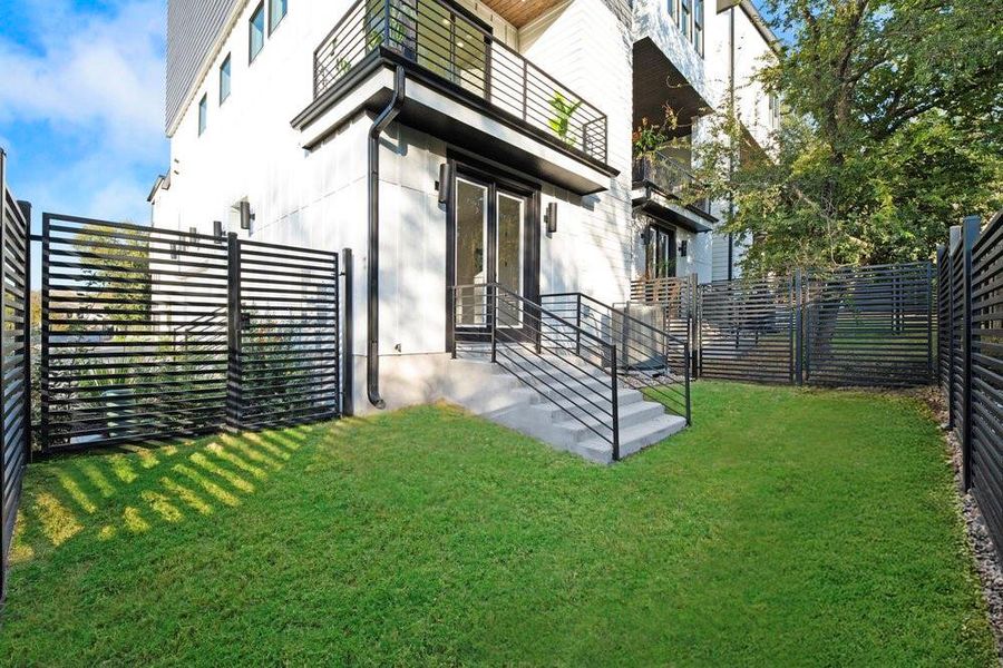 Back of property featuring a fenced backyard and a balcony