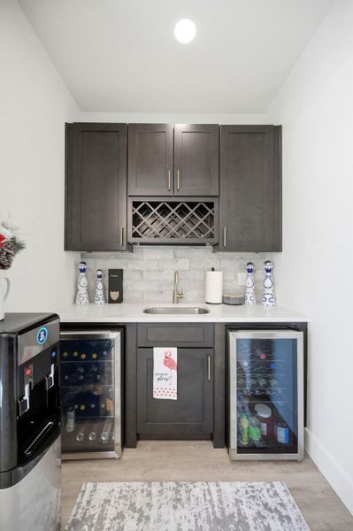 Dark cabinetry and dual beverage refrigerators elevate this functional home wet bar.