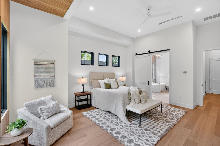 Hardwood floors and a high ceiling establish a refined ambiance in this tranquil primary suite.
