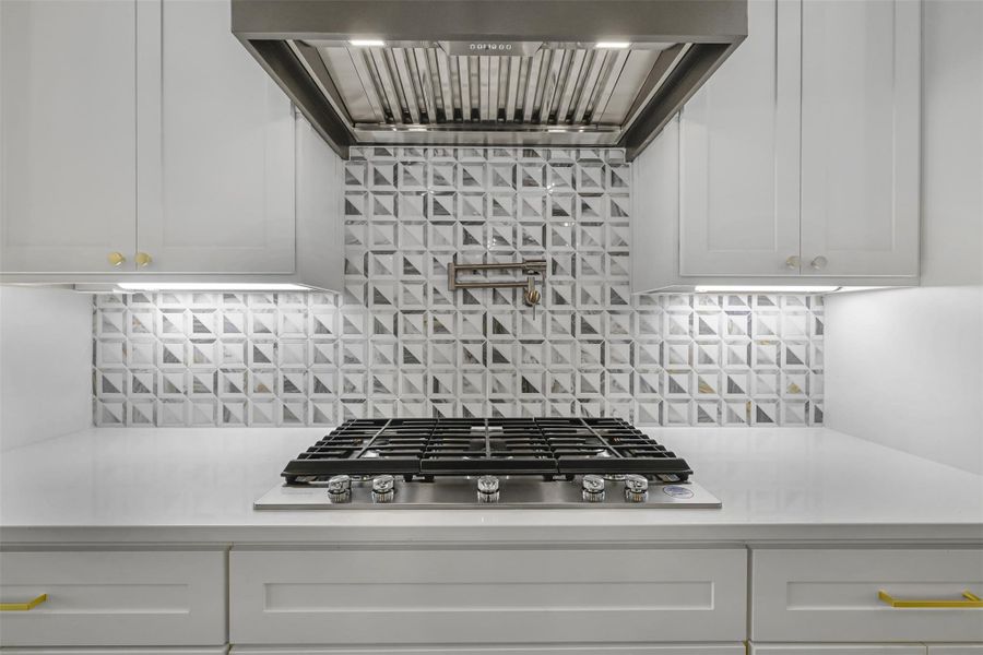 Kitchen featuring extractor fan, light countertops, white cabinetry, stainless steel gas stovetop, and backsplash