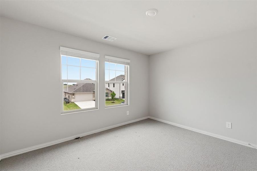 This room features light gray walls, a light gray carpet, and two large windows with horizontal blinds