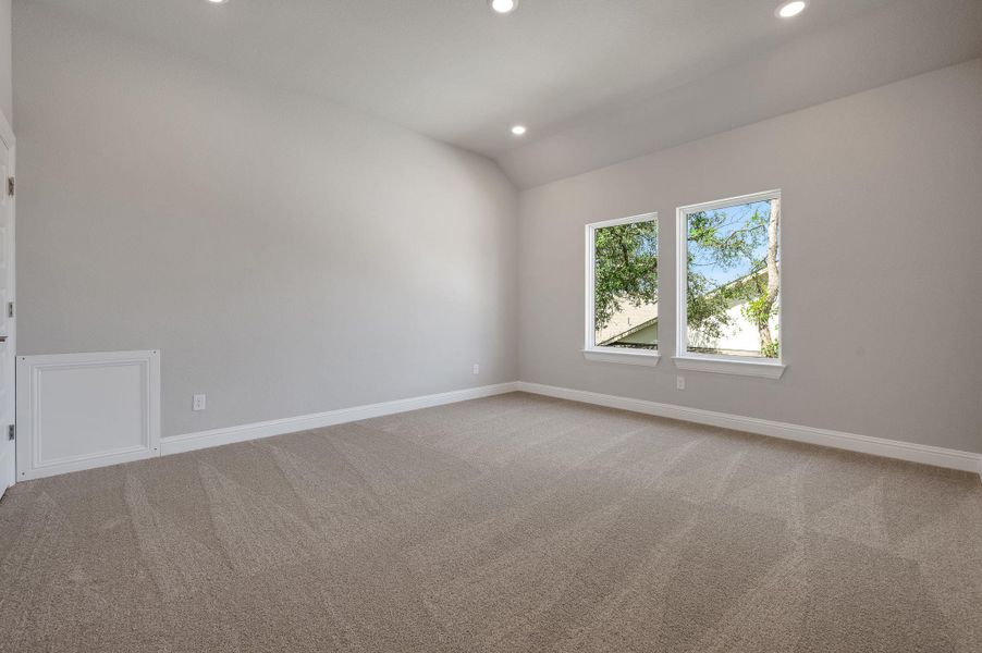 Carpeted empty room with vaulted ceiling and recessed lighting