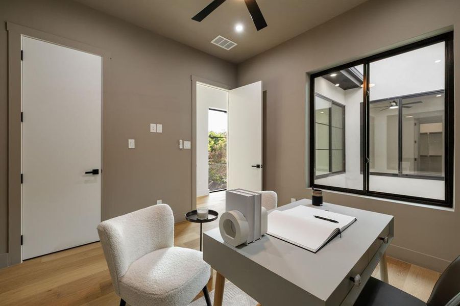 Modern interior room featuring light wood-finish flooring, a contemporary ceiling fan, and recessed lighting