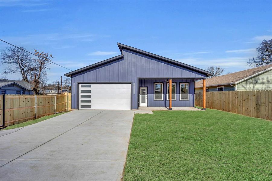 View of front facade with a garage, a front yard, and a porch