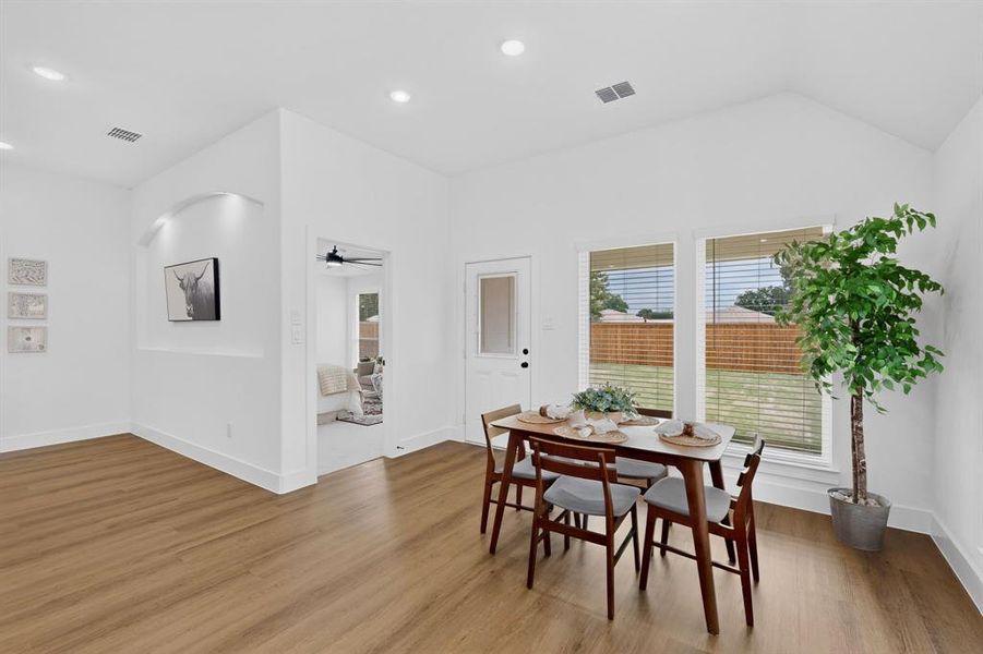 Open-concept dining area featuring wood-finish flooring, recessed lighting, and a vaulted ceiling
