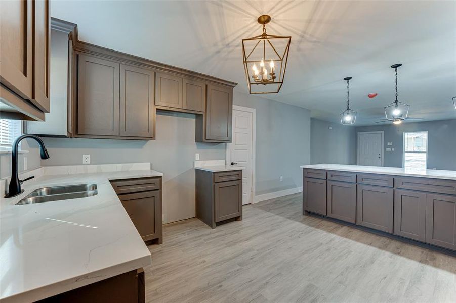 Kitchen featuring light stone countertops, sink, a wealth of natural light, and decorative light fixtures