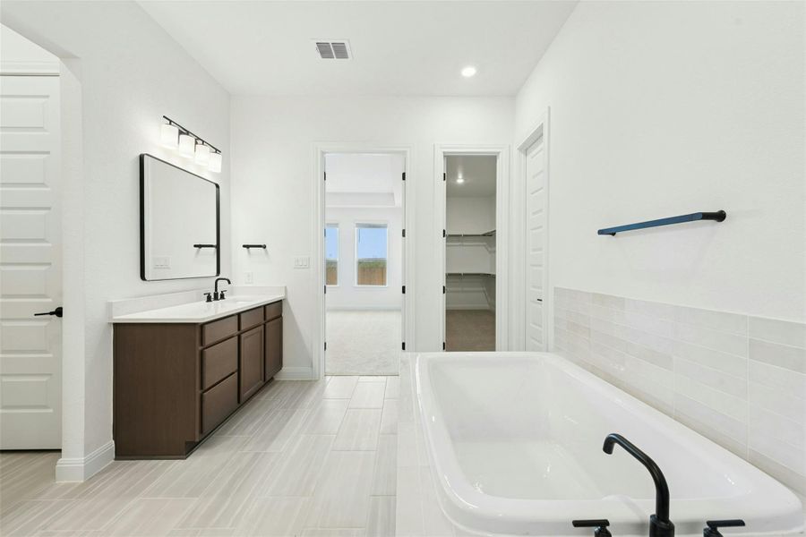 Bathroom with a walk in closet, vanity, a bath, and recessed lighting