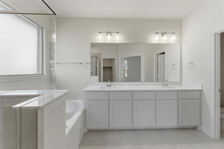Full bathroom with double vanity, a shower stall, and a garden tub