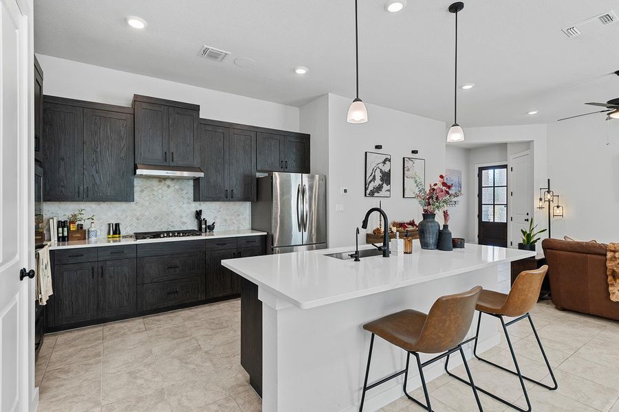 Kitchen featuring hanging light fixtures, tasteful backsplash, open floor plan, appliances with stainless steel finishes, and a breakfast bar area