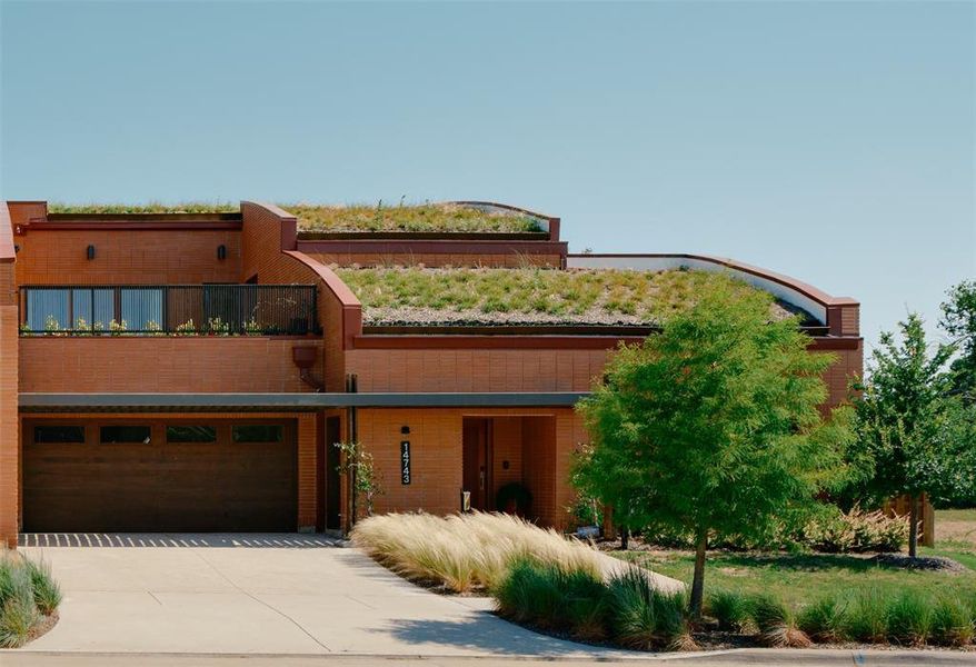 Contemporary home with a balcony, concrete driveway, brick siding, and a garage
