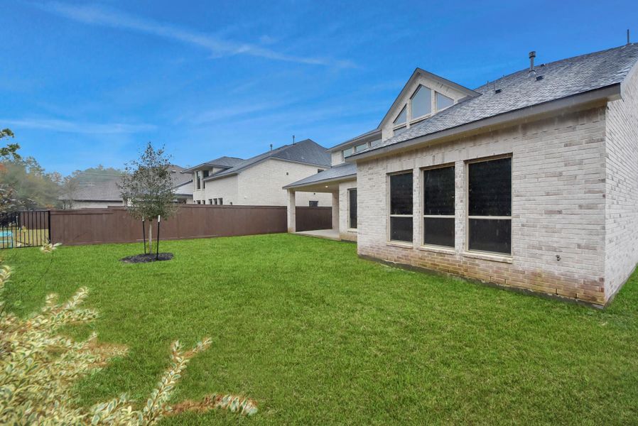 Spacious backyard with plenty of room for outdoor activities, complete with a covered patio and privacy fencing.
