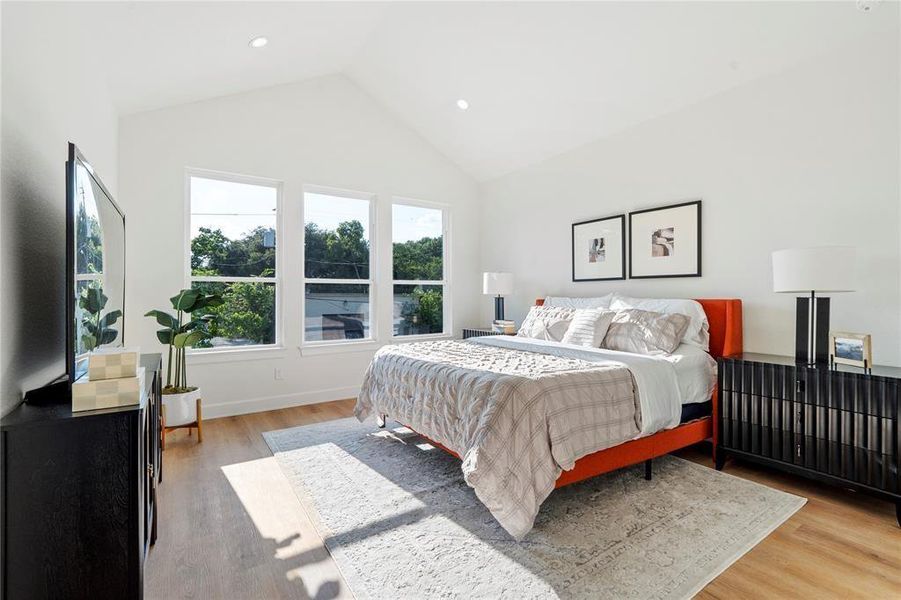 Sunlit bedroom with vaulted ceilings, featuring large windows, a cozy bed, and elegant furnishings. Sunlit bedroom with vaulted ceilings, featuring large windows, a cozy bed, and elegant furnishings.