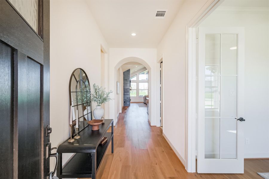 Beautiful entrance showcasing the home's hardwood floors and arched entrance to the open living areas.