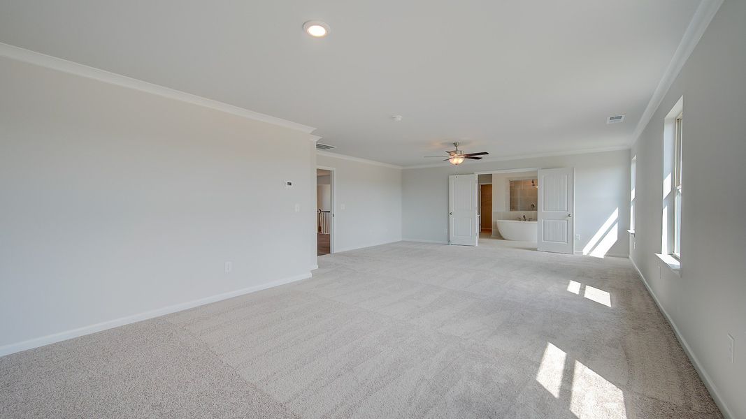 McKinley II primary suite with carpet flooring, natural light, and connected bath at Brighton in Locust Grove, GA.