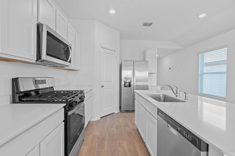 Kitchen featuring appliances with stainless steel finishes, recessed lighting, light wood finished floors, white cabinets, and light stone counters