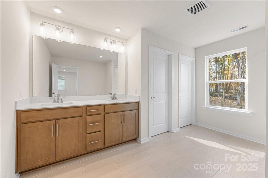 Primary Bath Featuring Stained Wood Cabinetry and Dual Vanity.