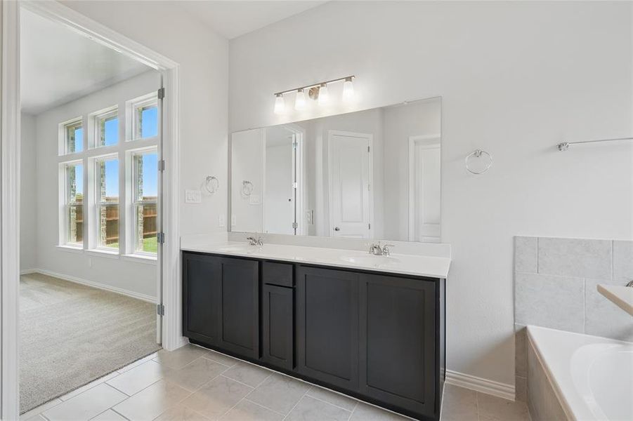 Full bath featuring double vanity, a bath, baseboards, and tile patterned flooring