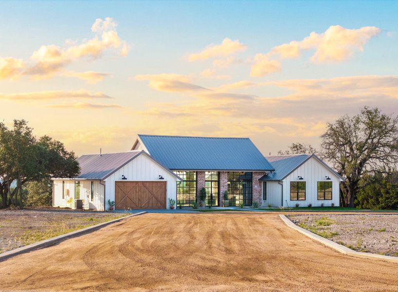 Modern farmhouse style home with board and batten siding, driveway, and a standing seam roof