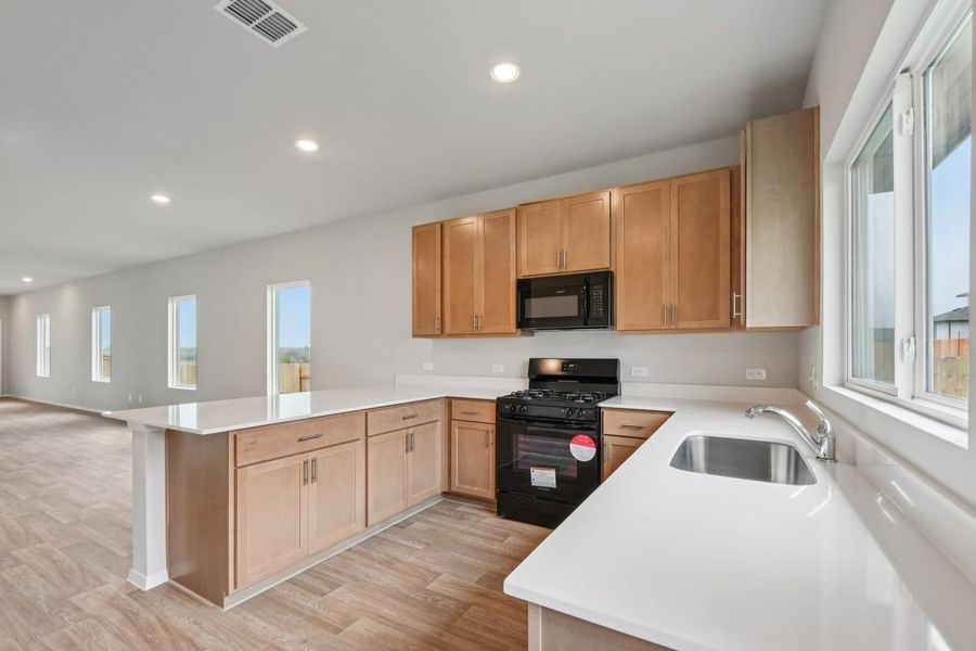 Image of a U-shaped kitchen with brown cabinets, and white countertops