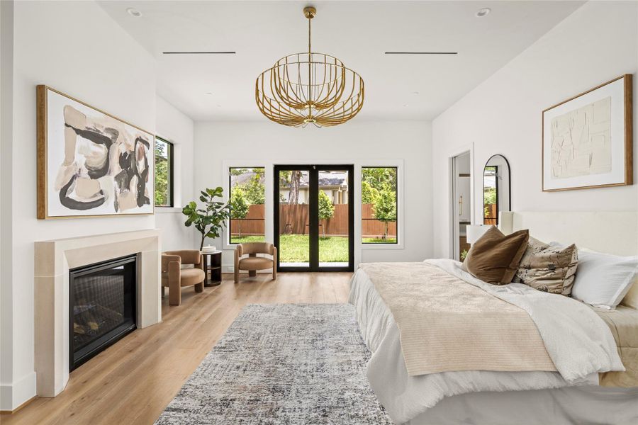 The large primary suite features high ceilings, elegant fireplace, chandelier, and private covered patio.