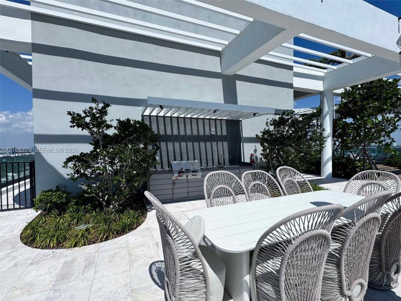 Expansive outdoor patio with white tile flooring and a built-in outdoor kitchen