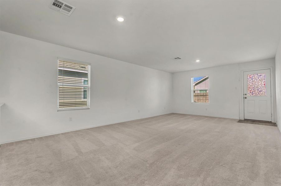 An open living space features wall-to-wall carpeting and recessed lighting. An open living space features wall-to-wall carpeting and recessed lighting.