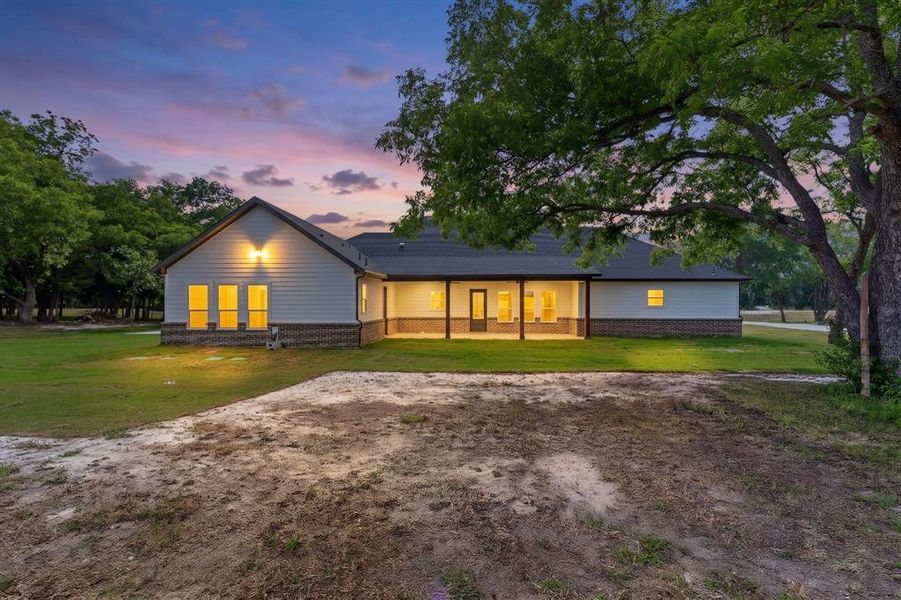 Contemporary single-story residence featuring a covered patio, white siding, and a brick foundation