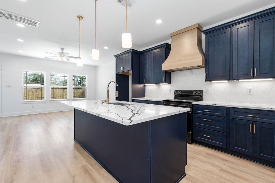 Open-concept kitchen featuring a large island, quartz countertops, and ash blue cabinetry.