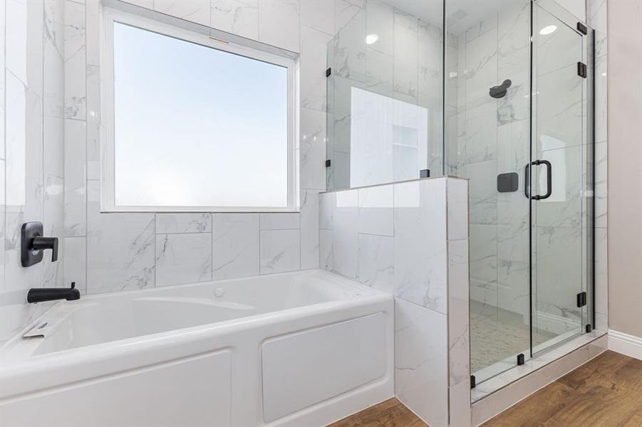 Bathroom featuring plus walk in shower, hardwood / wood-style flooring, and plenty of natural light