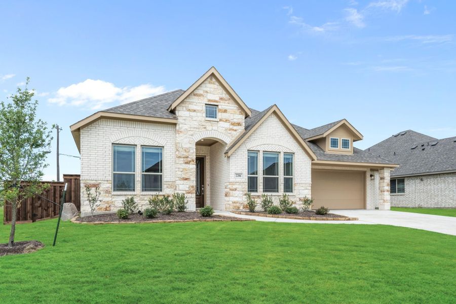 Single-story home with white brick and stone exterior, arched entry, two-car garage, and green front lawn