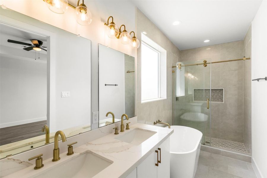Luxurious primary bathroom with dual vanities, a freestanding soaking tub, and a walk-in glass shower accented with gold fixtures. Luxurious primary bathroom with dual vanities, a freestanding soaking tub, and a walk-in glass shower accented with gold fixtures.