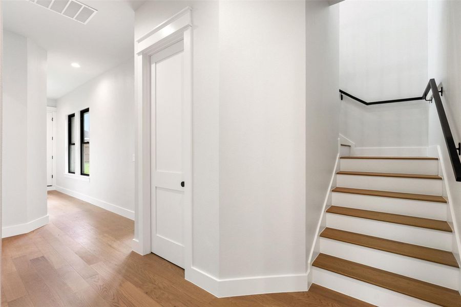 Clean lines define this luminous entryway, featuring warm wood flooring and a modern staircase.