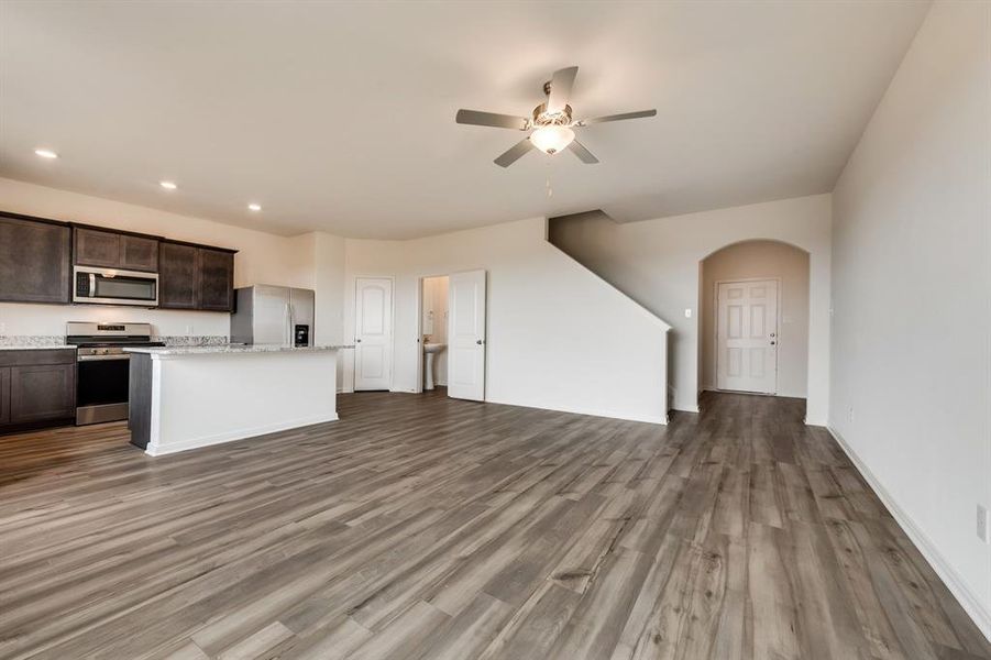 Kitchen featuring dark brown cabinets, ceiling fan, hardwood / wood-style floors, a kitchen island, and appliances with stainless steel finishes