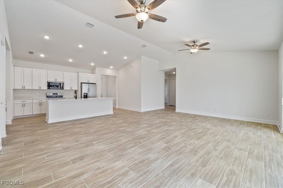 Unfurnished living room featuring recessed lighting, vaulted ceiling, a ceiling fan, and wood finish floors