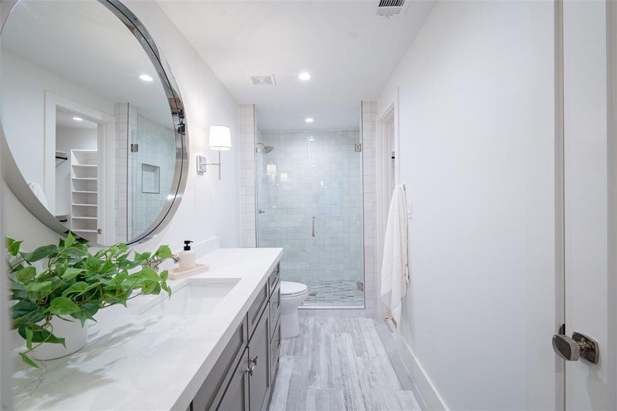 Bathroom featuring vanity, toilet, a shower with door