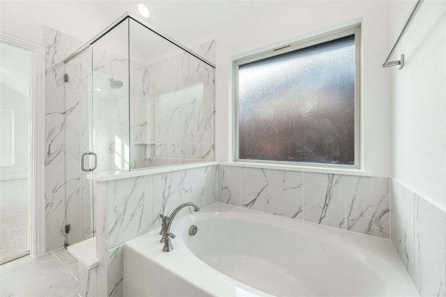 Bathroom with soaking tub, glass-enclosed shower, and white marble tile walls