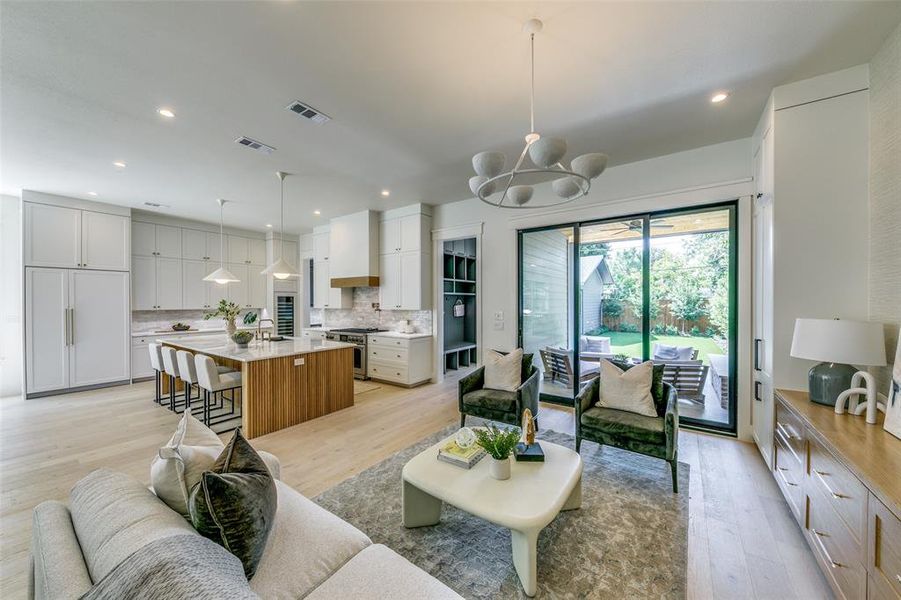 Living room featuring sink, light wood-type flooring, and a notable chandelier