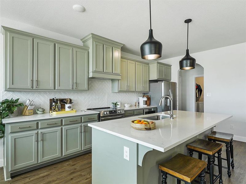 Kitchen with a center island with sink, stainless steel appliances, hanging light fixtures, a breakfast bar, and sink