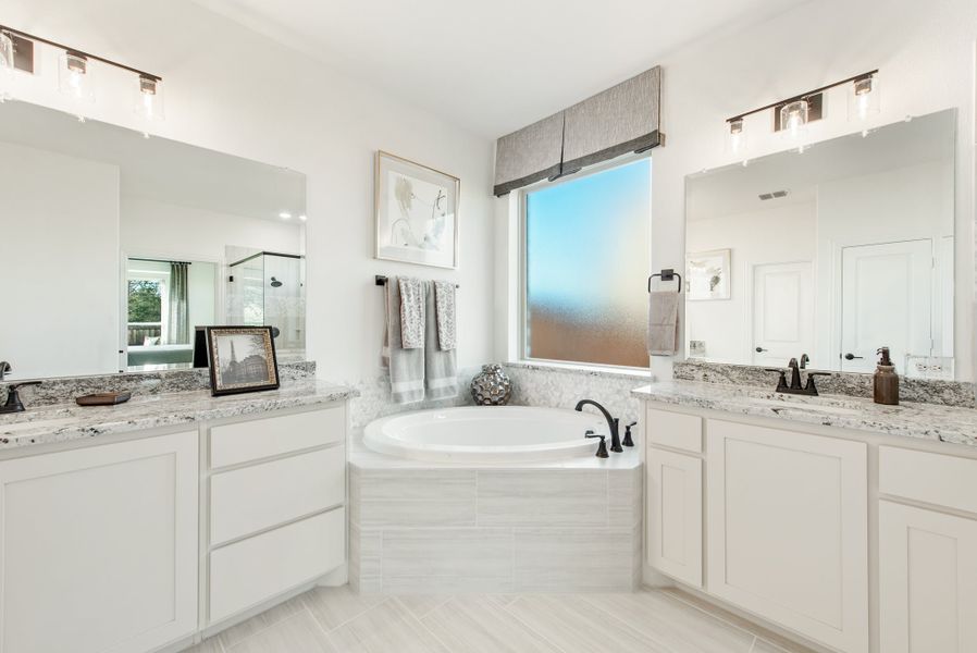 Master bathroom with dual vanities, granite countertops, and a soaking tub between white cabinets Master bathroom with dual vanities, granite countertops, and a soaking tub between white cabinets