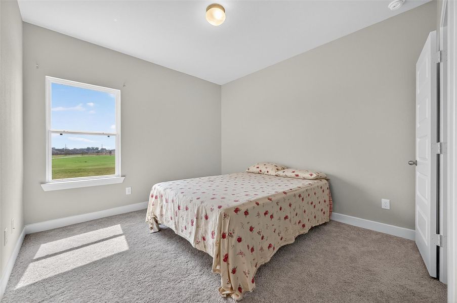 This comfortable secondary bedroom is filled with natural light and features soft carpeting and a spacious layout. A serene space ideal for restful nights or flexible use.
